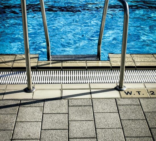 Piscine usée entourée de verdure luxuriante.